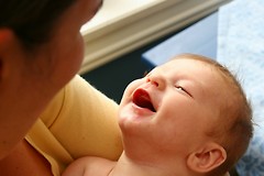 Mamma holder en leende baby i armene og ser på den