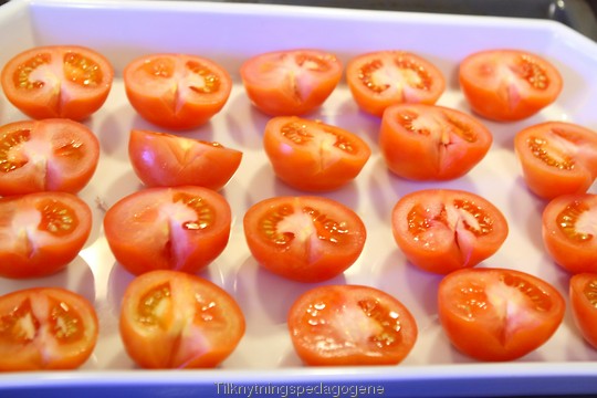 Halve tomater på et brett, klare for baking