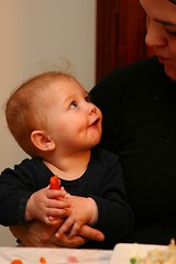 En halvt år gammel baby ser på mamma mens hun spiser gulrot