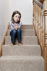 Ensom jente som sitter tankefull i trappen