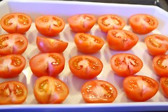 Halve tomater på et brett, klare for baking