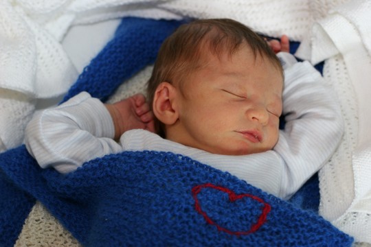 Liten baby sover i et hjemmestrikket ullpledd