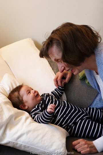 Baby leker med bestemor på sofaen